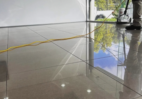 Floor polishing machine operator buffing high gloss tiles in a Botany automotive detailing bay.