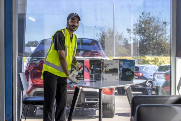 Kowhai Cleaning staff sanitising customer-facing surfaces inside a vehicle showroom in NZ, delivering reliable surface disinfection and presentation cleaning.