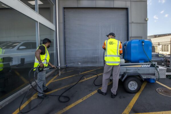 Team of exterior cleaners carrying out industrial pressure washing of roller doors at a commercial facility in Auckland, part of Kowhai’s full-service building wash solutions.