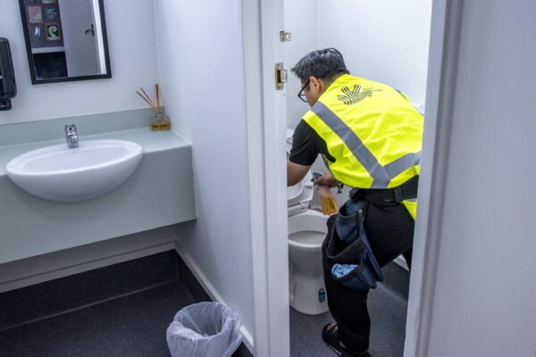 Professional commercial cleaner disinfecting a toilet at a New Zealand facility, delivering expert hygiene and washroom cleaning services.